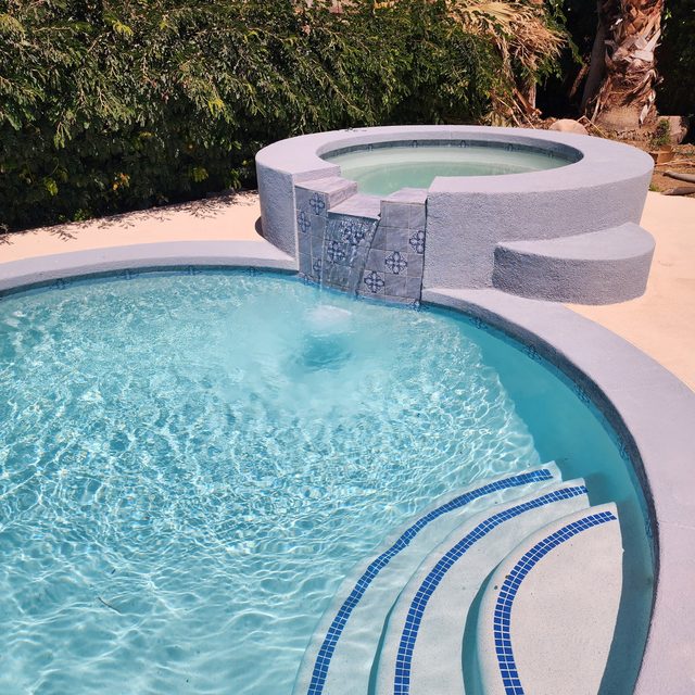 Finished pool remodel with new plaster, blue tile steps, and spa spillway